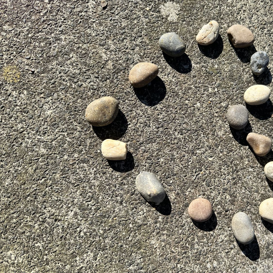 Pequeñas piedras formando un corazón sobre la arena de una playa.