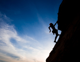 Rock climber clinging to a cliff.